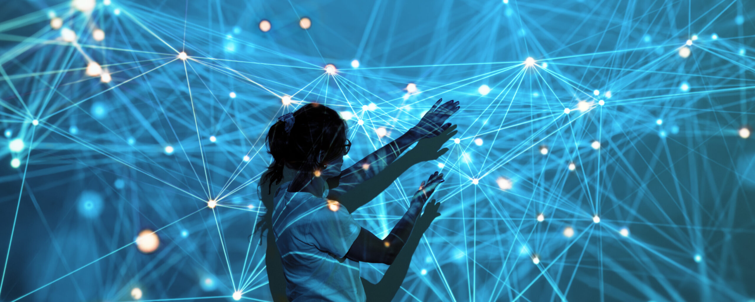 Pääkuva turkoosilla taustalla, jossa loistava verkosto kultaisilla pisteillä. Nainen on keskellä digitaalista verkostoa, joka heijastuu häneen ja jota kohti hän kurkottaa. Hän on sivuttain osittain selin kameraan.